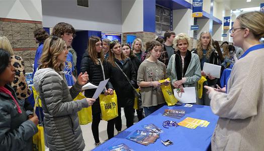 students and parents attend admitted student day, standing in front of an information booth